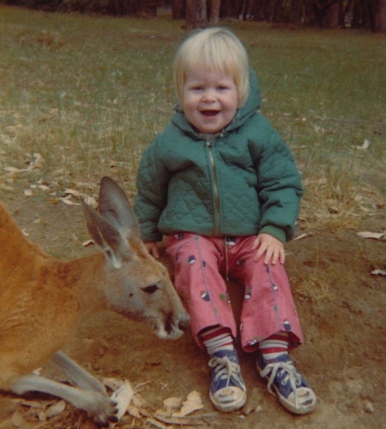Benjamin as a toddler in Australia, sitting on the grass beside a kangaroo